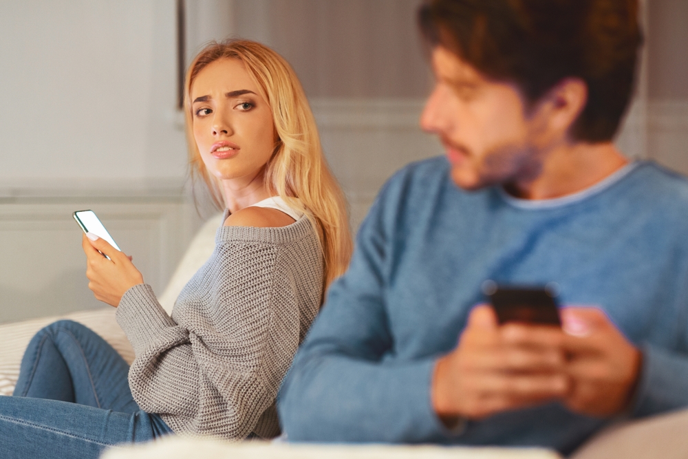 Couple on couch being sneaky on their phone